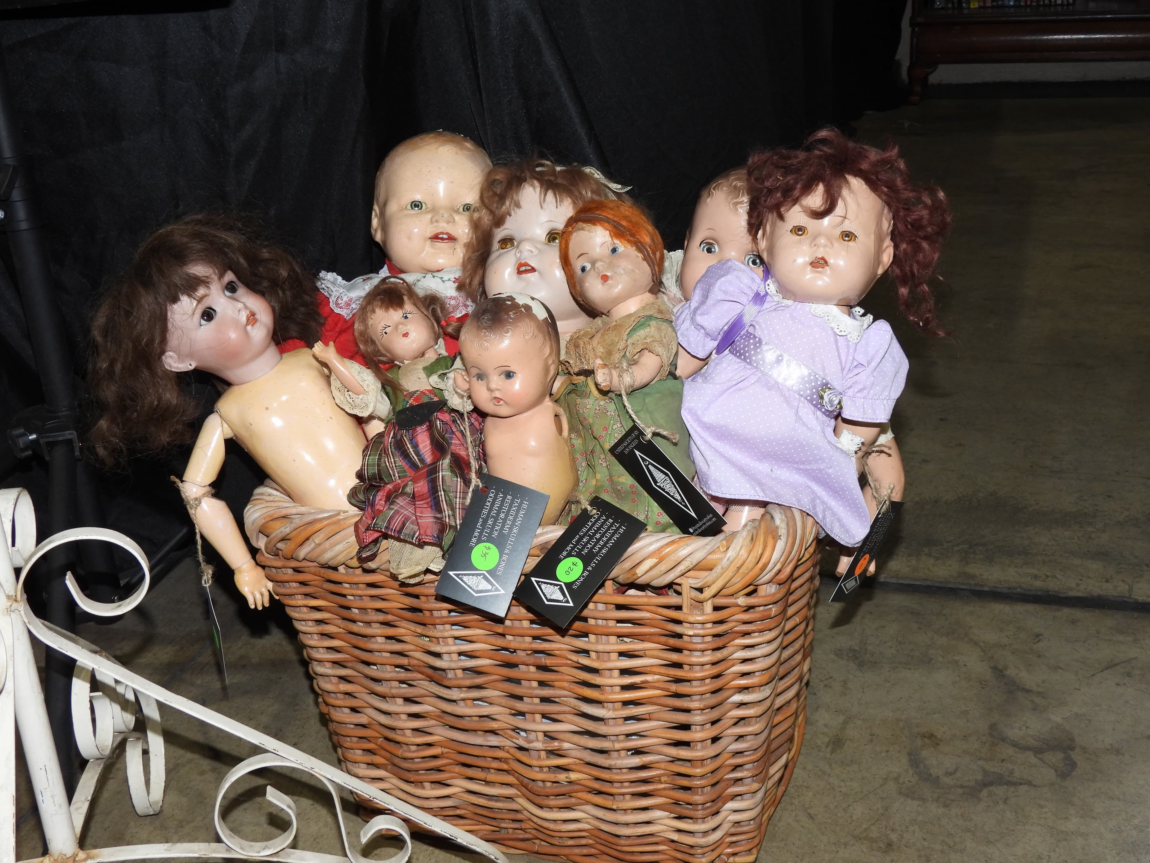 A group of old dolls arranged together in a wicker basket at a tattoo show