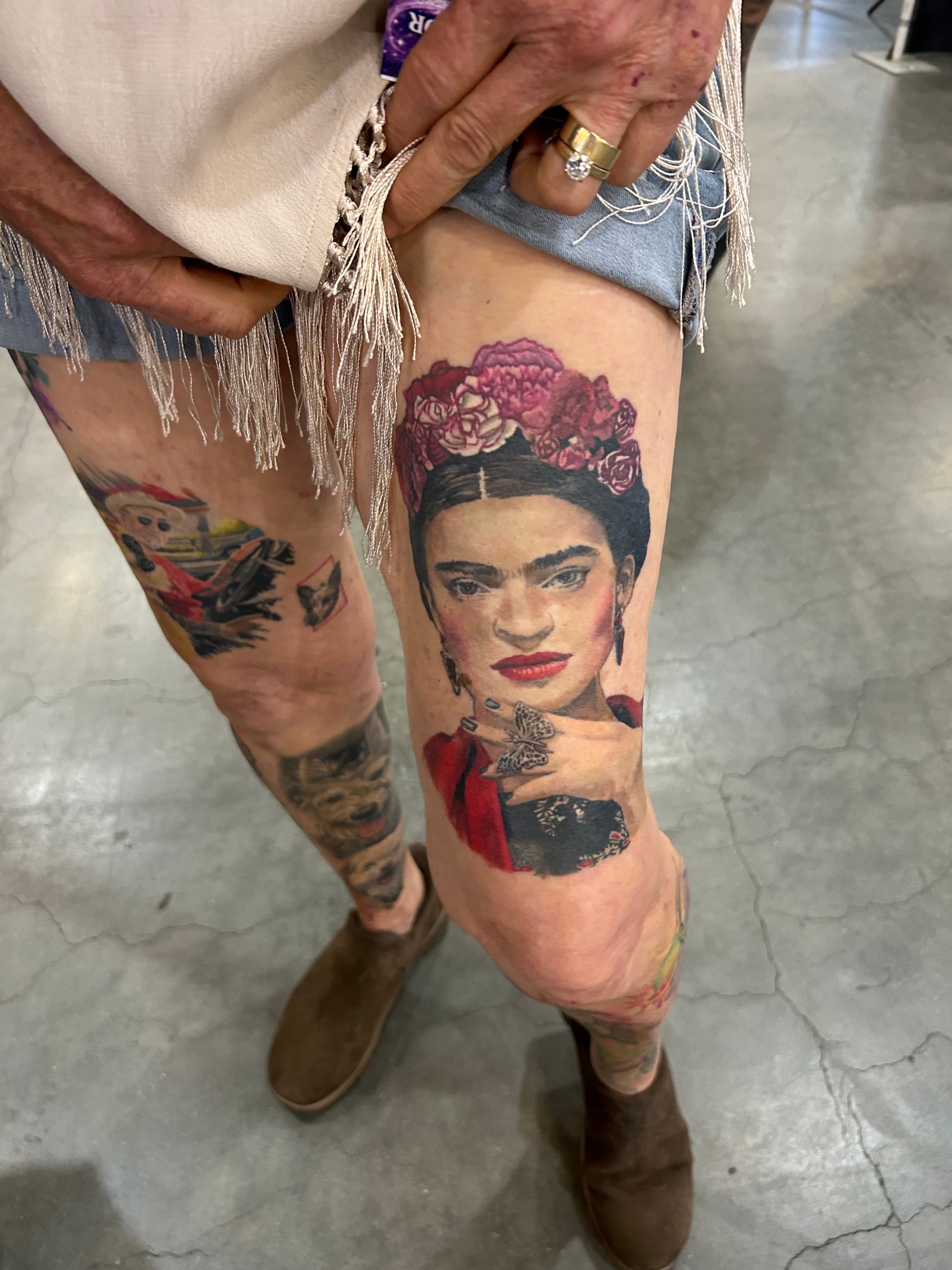 Frida Kahlo portrait tattoo with colorful flowers on Ann’s thigh, photographed at a tattoo convention