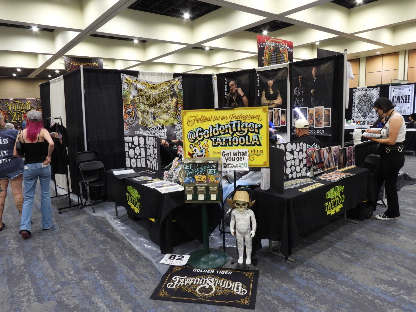 Show Me Your Dick - Why Great Tattoo Work Still Has to Win the Aisle Altered Flesh Tattoo convention booth with artwork, merchandise, and a skeleton mummy wearing a cowboy hat