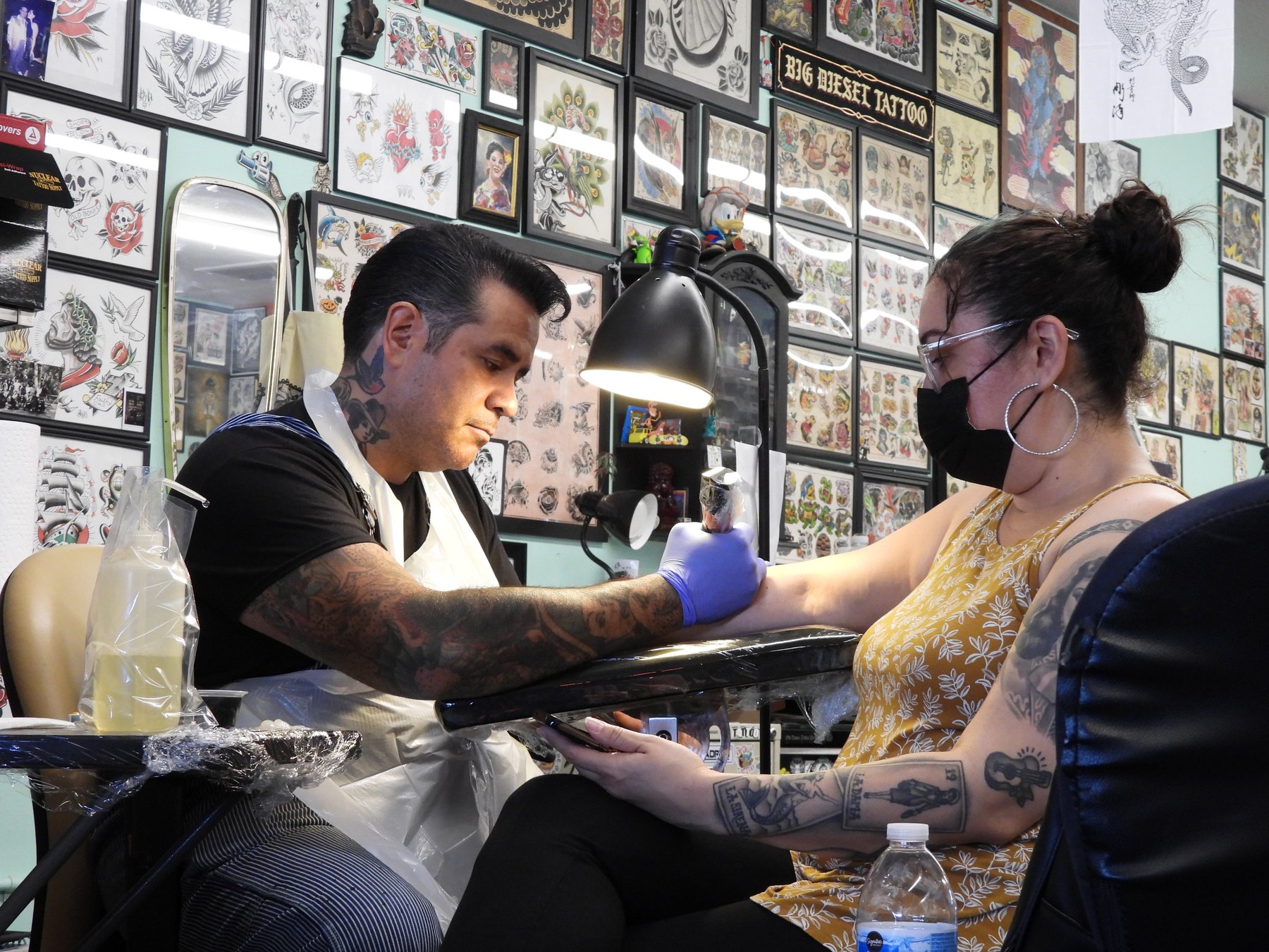 The Quiet Agreement — Trust, Craftsmanship, and the Relationship Behind the Ink Tattoo artist Bud tattooing Kathy inside Boom Boom Tattoo Room, showing the trust between artist and repeat client